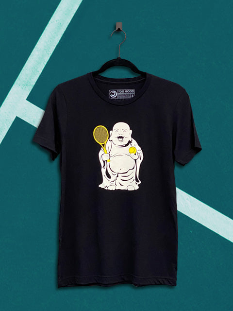 Black graphic short-sleeve tennis t-shirt with a tan buddha graphic on the front holding a yellow ball and racquet. The graphic tennis t-shirt is hanging on a black hanger in front of a teal tennis court background.