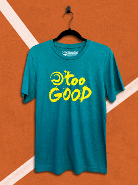 Teal t-shirt with a yellow graphic that says too good with a ball mark, hanging from a black hanger in front of an orange tennis court background.